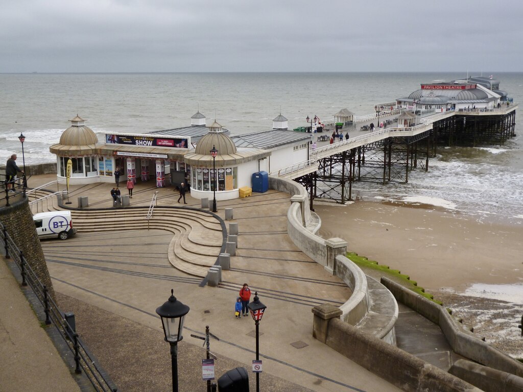 Visitors on Cromer beach with the Victorian pier in the background, north Norfolk